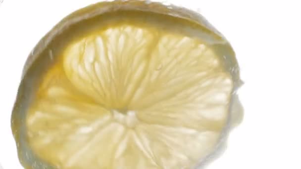 Замедленная съемка лимонного ломтика, падающего в холодную воду из стекла — стоковое видео