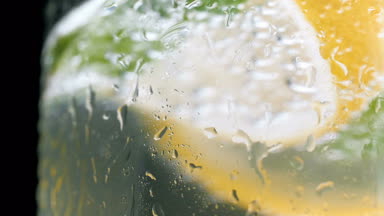 Su prolets bardak soğuk limonata siyah arka plan üzerinde makro ağır çekim görüntüleri