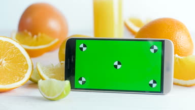 Smartphone tablo portakal, limon ve limon dolu anahtar ekranında yeşil renk ile portre görüntüleri. Mükemmel video ekleme
