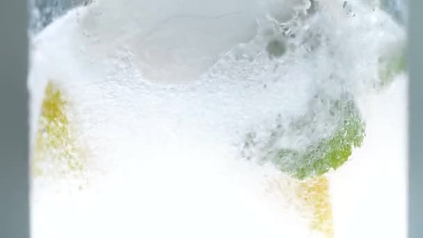 Imágenes en cámara lenta de agua de soda vertiendo lentamente en un vaso con limones, menta y hielo — Vídeo de stock