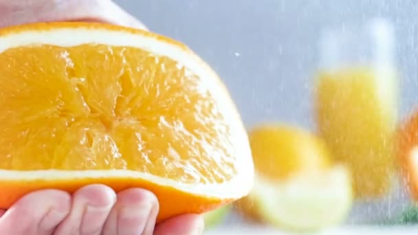 Замедленная съемка, где рука сжимает апельсин. Соки лопаются и капают из цитрусовых . — стоковое видео