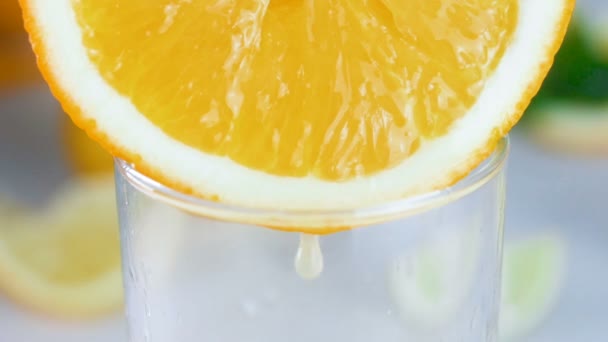 Primo piano riprese al rallentatore di succo fresco sgocciolante da arancia fresca in vetro — Video Stock