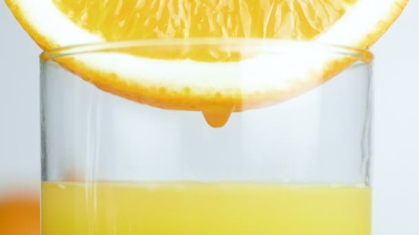 Primer plano imágenes en cámara lenta de gotitas cayendo lentamente en un vaso de jugo de naranja — Vídeos de Stock