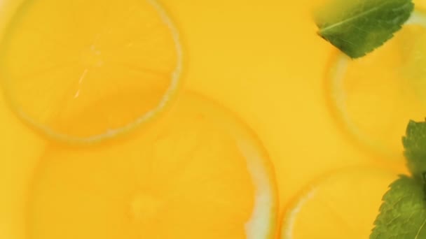 Closeup slow motion video of orange slices and mint leaves in lemonade