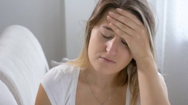 Kanepede oturan ve alnına elini tutarak genç hasta kadın portresi