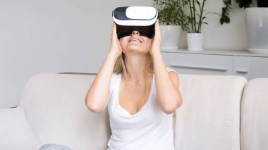 Güzel genç gülümseyen kadın kanepede oturan Vr gözlük takıyor