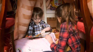 Yatak odası ve kitap okumak, çadırda oturan sevimli yürümeye başlayan çocuk portresi