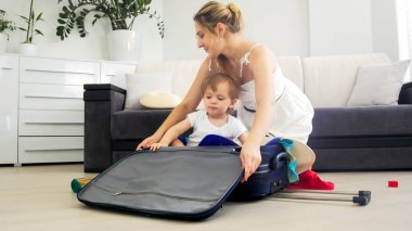 Bavul tatil için paketleme güzel genç anne ve yürümeye başlayan çocuk