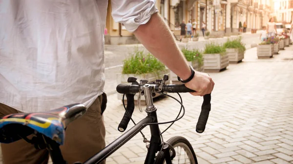 Foto tonica del giovane che si tiene per mano in bicicletta mentre cammina per strada — Foto Stock