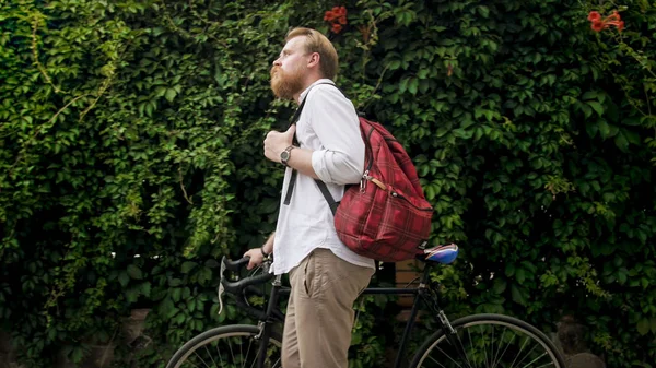 Portrait of handsome man with red backpack walking with bicycle — Stock Photo, Image