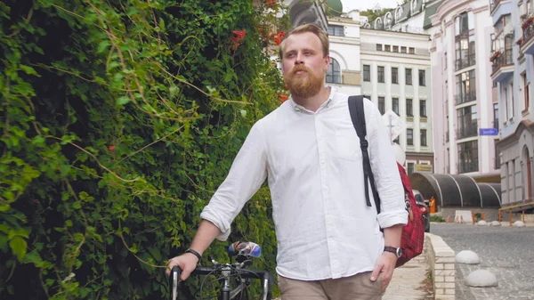 Retrato de jovem barbudo vermelho caminhando para o trabalho com bicicleta — Fotografia de Stock