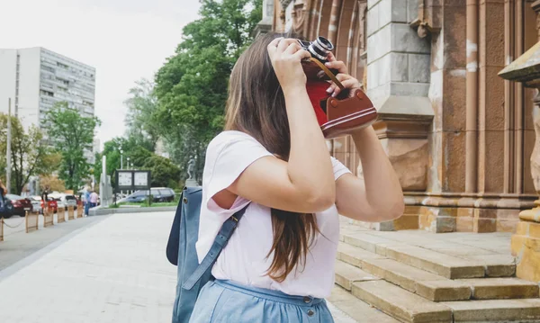 Beautiful brunette tourist girl making image of old cathedral on vintage film camera — Stock Photo, Image