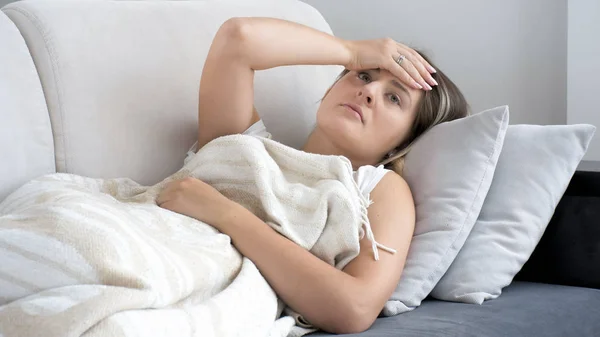 Baş ağrısı kanepe oturma odasında yatan genç esmer kadın portresi — Stok fotoğraf