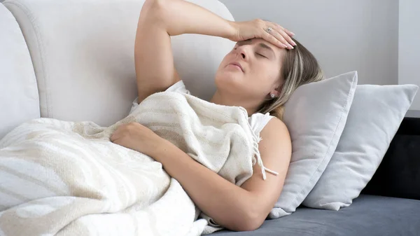 Photo d'une jeune femme migraine allongée sur un canapé à la maison — Photo