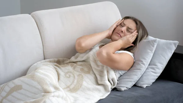 Porträtt av ung kvinna lider av huvudvärk liggande på soffan — Stockfoto