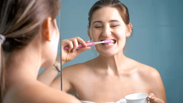 Retrato de jovem mulher sorridente escovando os dentes no banheiro — Fotografia de Stock