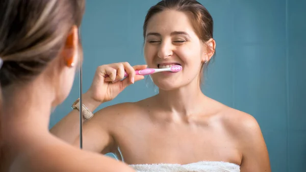 Foto de mujer sonriente feliz limpiando los dientes en la mañana en el baño —  Fotos de Stock