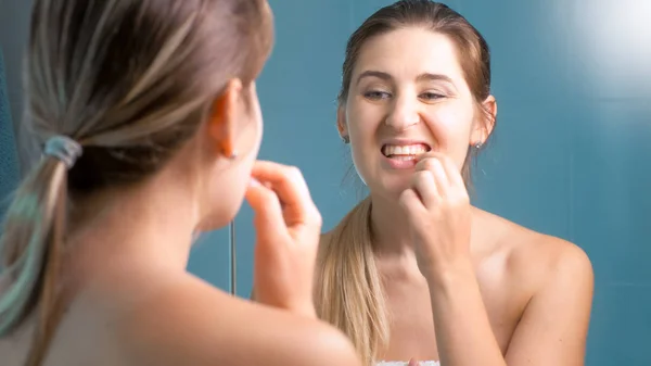 Porträtt av ung kvinna kontrollera tänderna på spegel — Stockfoto
