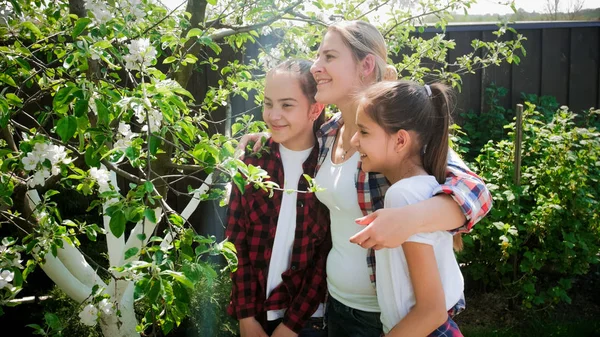 Portret van gelukkige jonge familie poseren in boomgaard op zonnige dag — Stockfoto