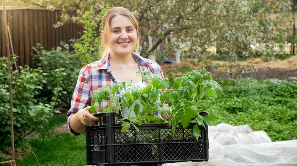 Retrato de mujer jardinero feliz sosteniendo cajón con plántulas — Foto de Stock
