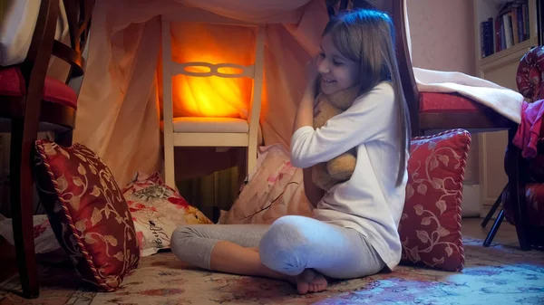 Милая маленькая девочка с плюшевым мишкой в палатке вигвама на ночь — стоковое фото