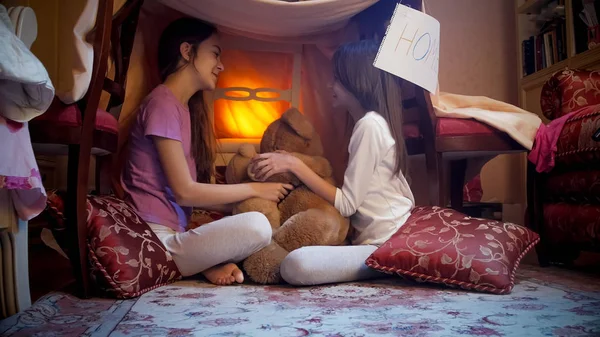 Two teenage girls sitting in tepee tent in bedroom at night — Stock Photo, Image