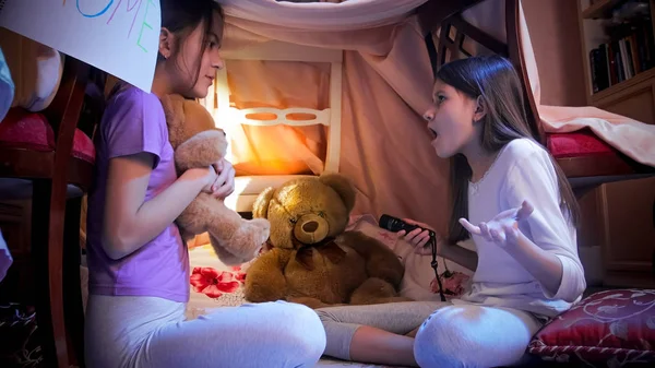 Duas meninas brincando na tenda tepee no quarto e contando histórias assustadoras — Fotografia de Stock