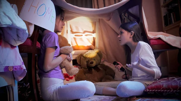 Adolescentes com lanterna falando na barraca auto-feita no quarto — Fotografia de Stock