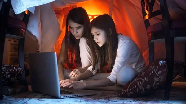 Two girls in pajamas using laptop at night — Stock Photo, Image