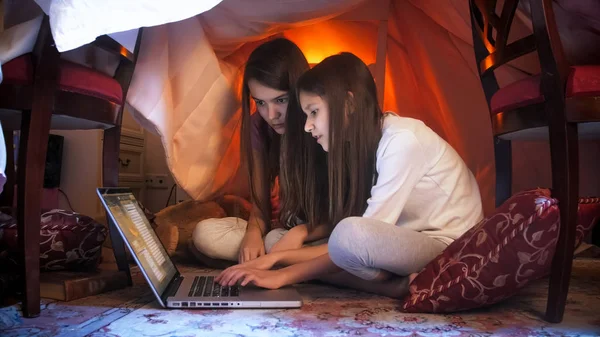 Two girls with laprop in tepee tent at night — Stock Photo, Image