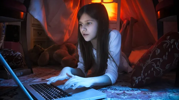 Retrato de menina bonito deitado no chão à noite e usando laptop — Fotografia de Stock