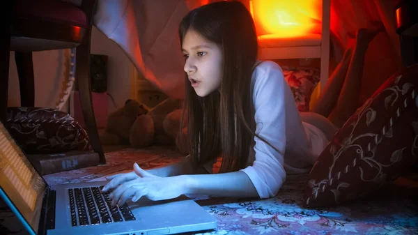 Portret van tienermeisje in tent gemaakt van dekens met laptop — Stockfoto