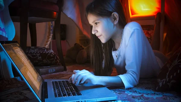 Porträt eines lächelnden Mädchens im Schlafzimmer, das nachts soziale Medien auf seinem Laptop nutzt — Stockfoto