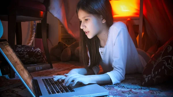 Retrato de linda chica con portátil tumbado en el suelo por la noche —  Fotos de Stock