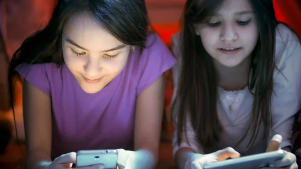 दो किशोर लड़कियों की क्लोजअप फोटो तल पर पड़े और रात में मोबाइल फोन का उपयोग करते हुए — स्टॉक फ़ोटो, इमेज