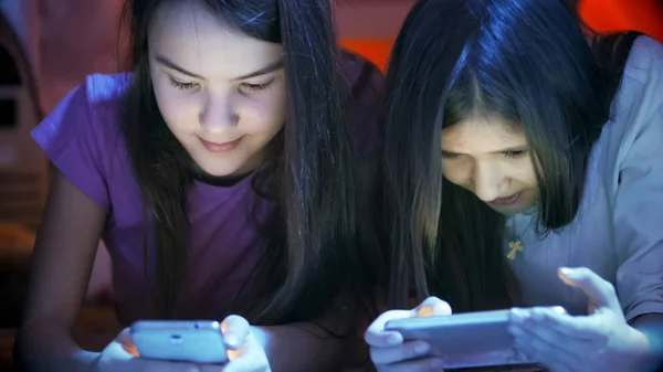 Närbild porträtt av två tonårsflickor med mobiltelefoner på natten — Stockfoto