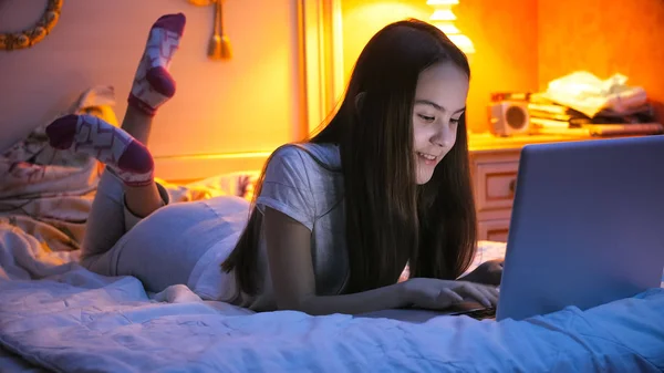 Retrato de una adolescente sonriente acostada en la cama y charlando en internet —  Fotos de Stock