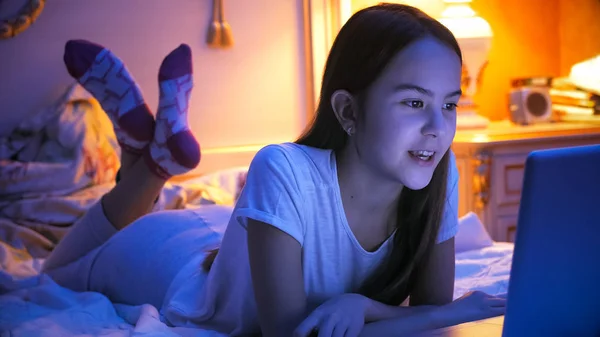 Retrato de menina adolescente deitada na cama à noite com laptop — Fotografia de Stock