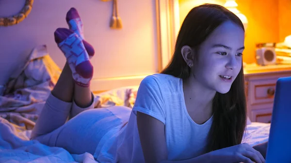 Porträtt av tonårig flicka liggande på sängen på natten och chatta på internet — Stockfoto