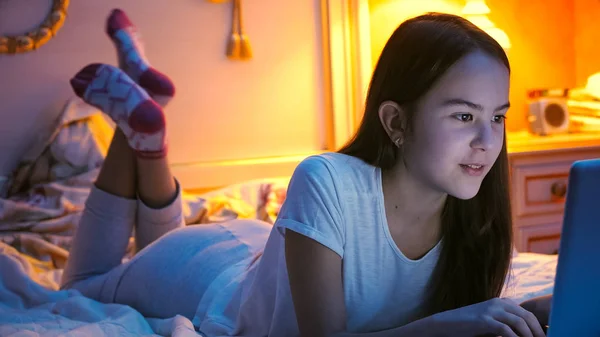Portret pięknej dziewczyny, leżąc na łóżku w nocy i przy użyciu komputera — Zdjęcie stockowe