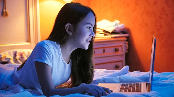 Porträtt av leende tonårsflicka med video talk på laptop på natten — Stockfoto