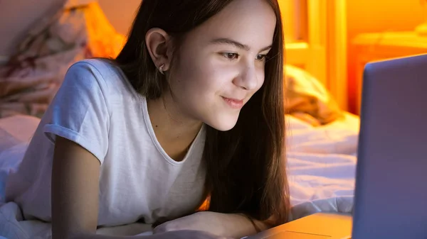 Retrato de menina bonita morena usando laptop na cama à noite — Fotografia de Stock