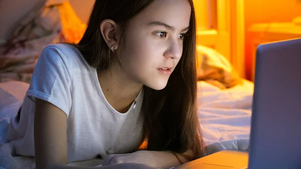 Retrato de menina morena deitada na cama e assistindo filme no laptop — Fotografia de Stock