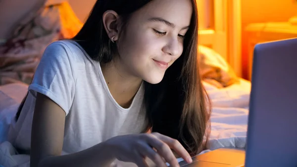 Retrato de hermosa chica en pijama mintiendo y escribiendo mensaje en el ordenador portátil —  Fotos de Stock