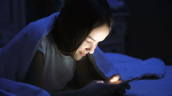 Tipik haber üstünde hareket eden telefon geceleri güzel gülümseyen kız portresi — Stok fotoğraf