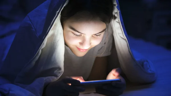 Battaniye ile smartphone altında gülümseyen kız portresi — Stok fotoğraf