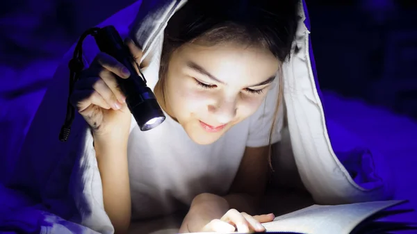 Närbild foto av tonårsflicka läsebok med under filt med ficklampa — Stockfoto