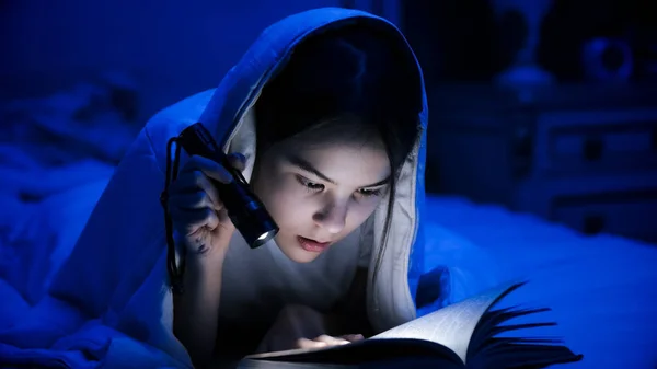 Retrato de livro de leitura menina no quarto escuro com lanterna — Fotografia de Stock