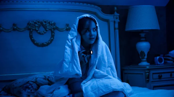 Retrato de menina coberta de cobertor à procura de monstros com lanterna — Fotografia de Stock