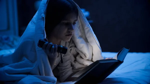 Porträtt av flicka läsebok i mörkt rum innan du somnar — Stockfoto